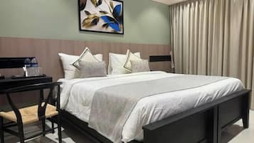 A hotel room with a bed, a nightstand, a chair, and a painting on the wall.