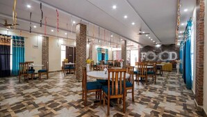 A restaurant with multiple dining areas, brick pillars, and patterned flooring.