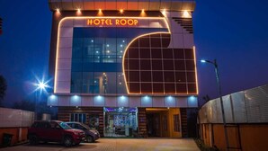 A modern hotel with a prominent "HOTEL ROOP" sign, featuring a large glass facade and a curved architectural element.
