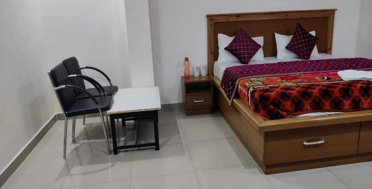 A bedroom with a bed, a bedside table, a chair, and a small table.