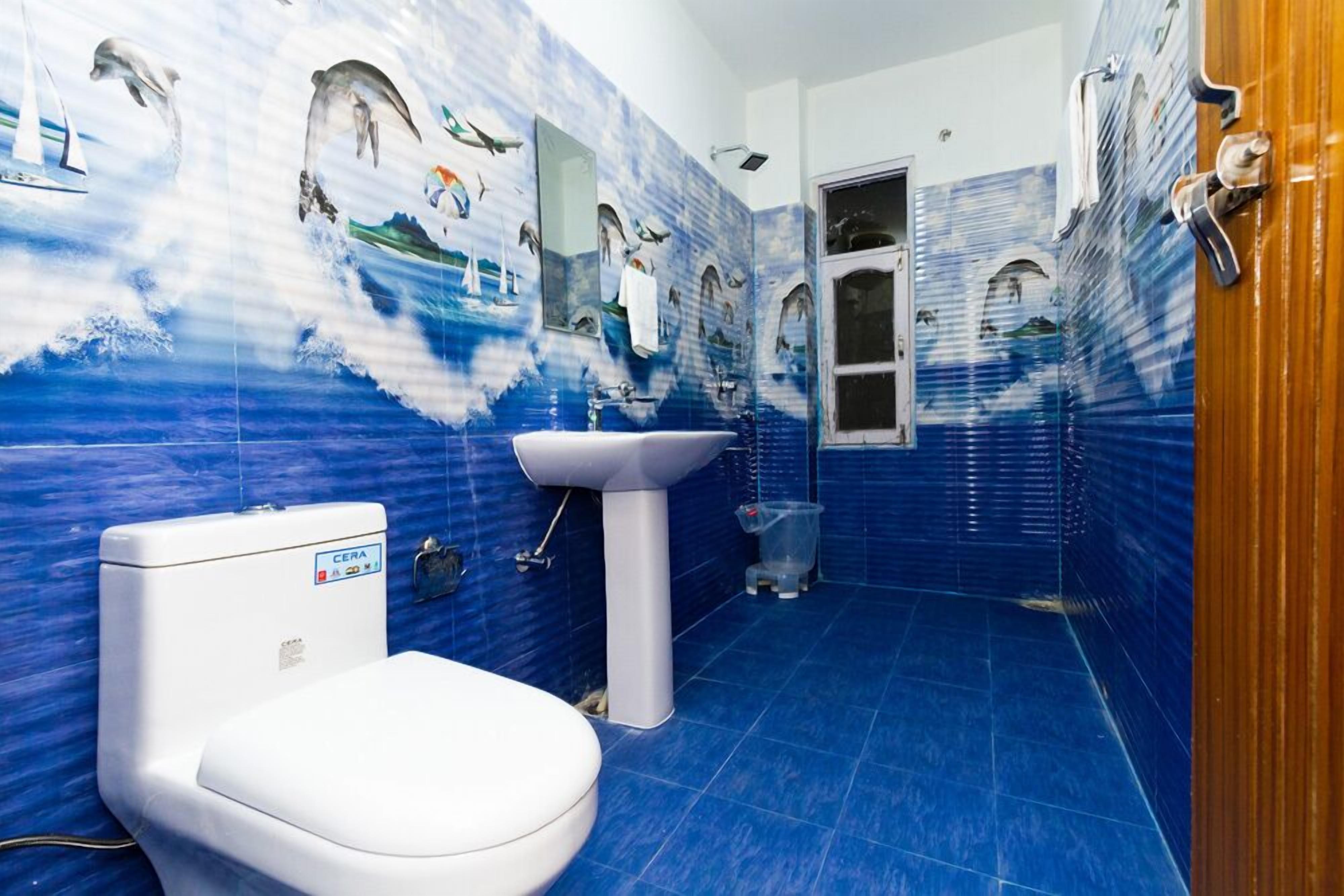 Un baño con piso y paredes de azulejos azules, un inodoro blanco y un lavabo.