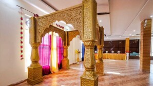 An ornate archway with intricate carvings, leading to a room with a polished wooden floor and a reception area in the background.