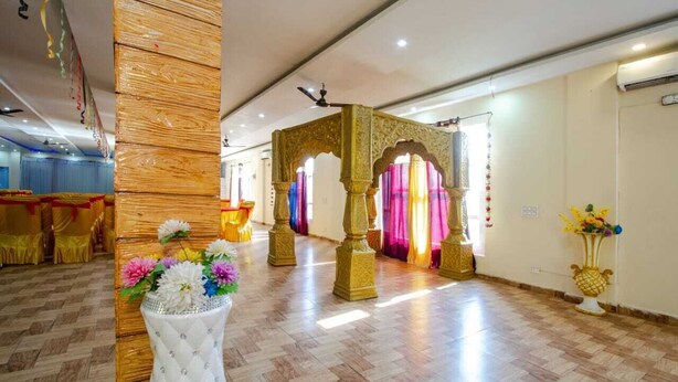 A hotel lobby with a wooden column, a decorative archway, and a floral arrangement.