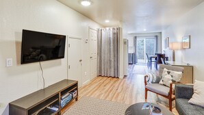 A living room with a flat-screen TV, a wooden entertainment unit, a grey sofa, and a patterned rug. - Airy Fortuna Apartment With Deck! (Fortuna)