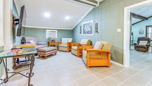 A spacious living area with a glass coffee table, multiple sofas, and a television. - Bunkhouse-style Studio in Elkins Near ATV Trails! (Combs)