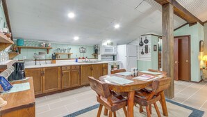 A kitchen with wooden cabinets, a dining table with chairs, a microwave, and a refrigerator. - Bunkhouse-style Studio in Elkins Near ATV Trails! (Combs)
