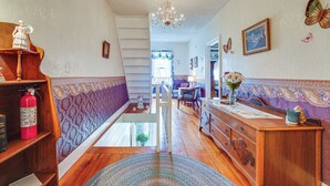 Ein Flur mit Treppe, Holzmöbeln, einem Chandelier und Wanddekorationen mit Schmetterlingen.