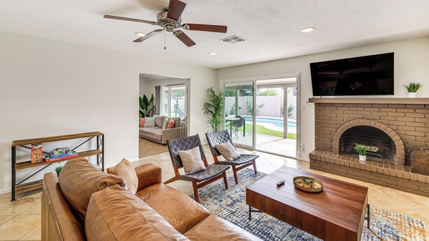 A spacious living room with a leather sofa, two armchairs, a coffee table, a fireplace, and a ceiling fan. - 6 Mi to TPC Scottsdale: Family Escape w/ Fire Pit! (Scottsdale)