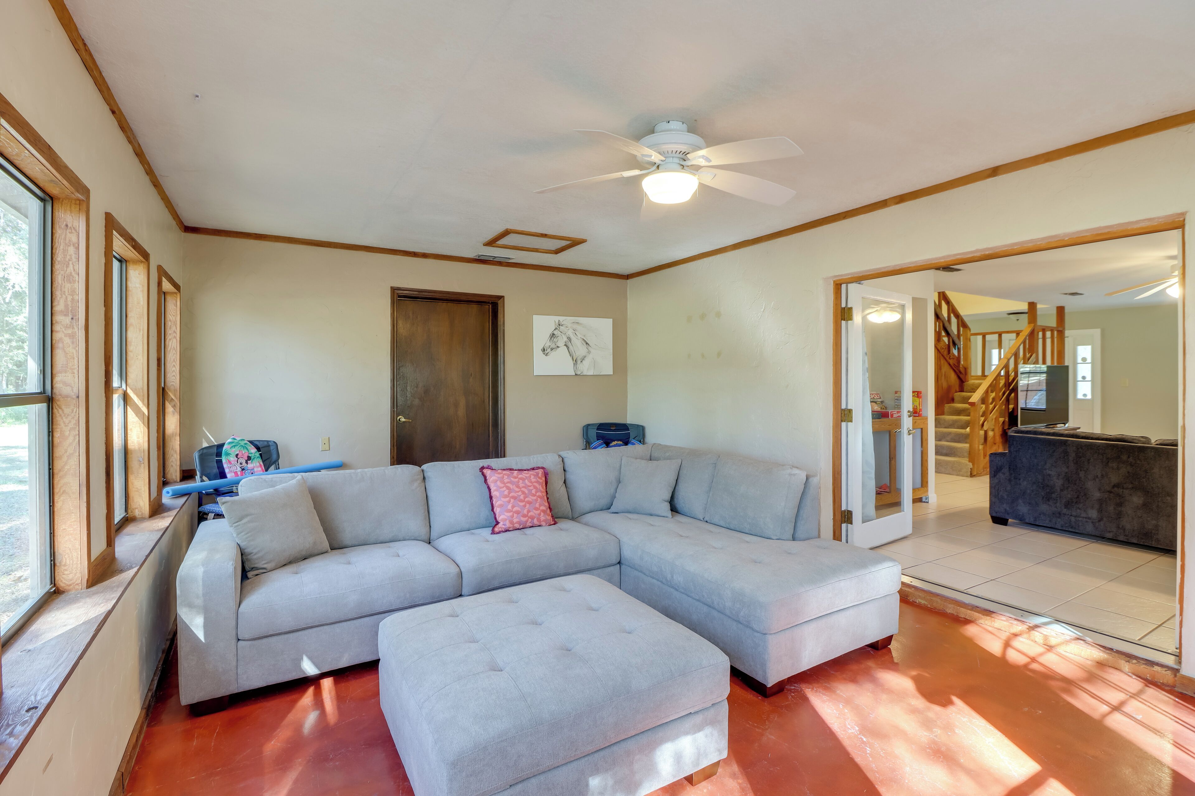 A spacious living room with a large sectional sofa, a ceiling fan, and a view into the kitchen area.