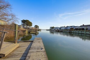 A wooden dock extending into calm water, surrounded by residential buildings and trees. - Private Dock: Fisherman's Paradise on Bass River (West Dennis)