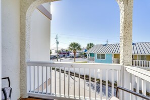 A balcony with a white railing overlooking a street with houses and a clear sky. - Panama City Beach Townhome w/ Deck, Ocean Views (Panama City Beach)