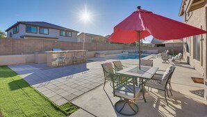 A backyard with a pool, patio furniture, and a red umbrella. - Spacious Phoenix Vacation Rental w/ Private Pool! (Phoenix)