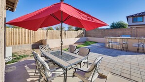 An outdoor patio with a table and chairs, a red umbrella, and a bar area. - Spacious Phoenix Vacation Rental w/ Private Pool! (Phoenix)