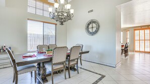 A dining area with a chandelier, a large wall clock, and a dining table set for four. - Spacious Phoenix Vacation Rental w/ Private Pool! (Phoenix)