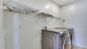 A laundry area with two front-loading washing machines, a drying rack with clothes, and a power outlet on the wall. - Spacious Phoenix Vacation Rental w/ Private Pool! (Phoenix)