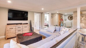 A modern living room with a large flat-screen TV, a wooden cabinet, a sofa set, and a coffee table. - Pet-friendly Narragansett Home w/ Deck + Gas Grill (Narragansett)