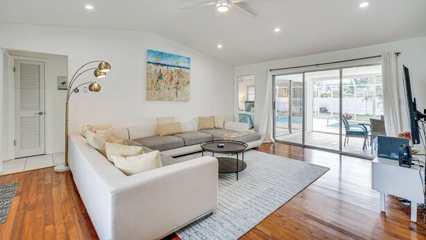 A spacious living room with a large sofa, a coffee table, and a ceiling fan.