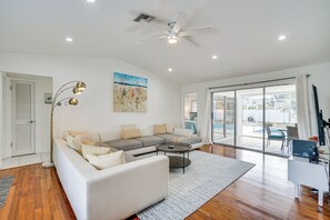 A spacious living room with a large sofa, a coffee table, and a ceiling fan. - Cozy Cape Coral Home w/ Pool: 1 Block to Canal! (Cape Coral)