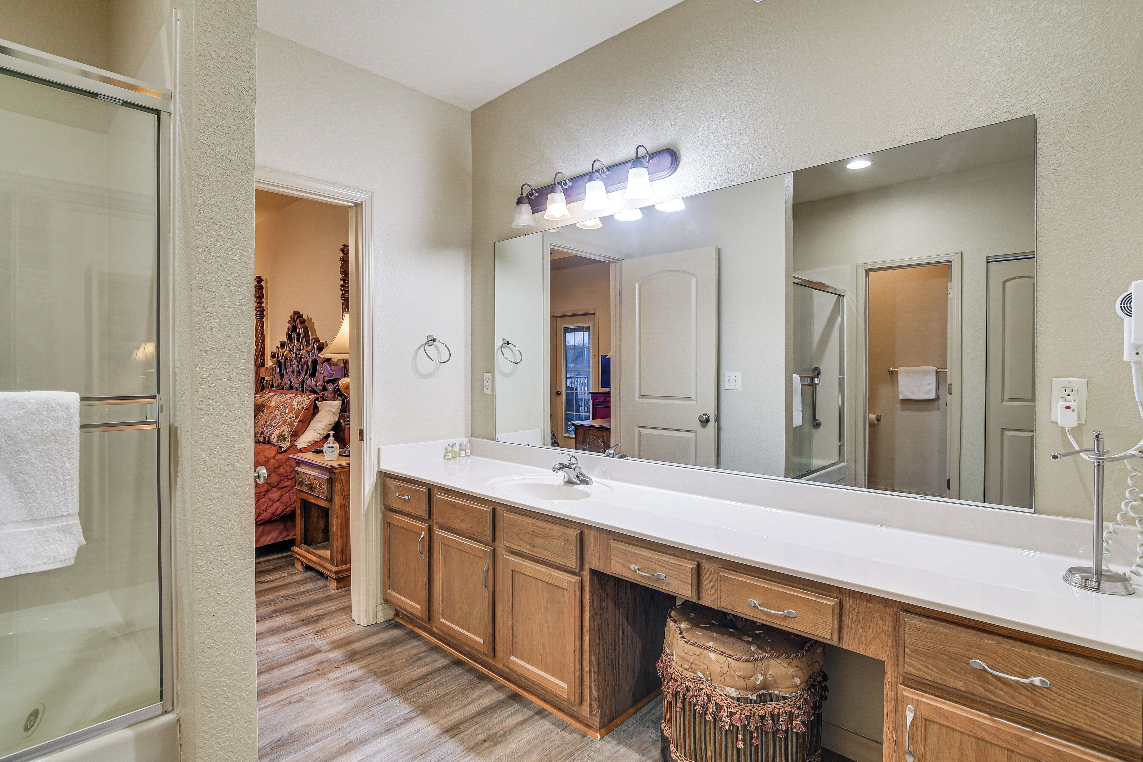 A bathroom with a large mirror, wooden vanity, and a glass shower enclosure.