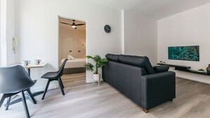 A modern living room with a sofa, chairs, a coffee table, a TV, and a painting on the wall. - Grace At Mosman - Service Apartments (Mosman)