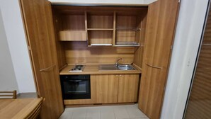 A compact kitchen with wooden cabinets, a built-in dishwasher, and a sink. - AH Roma (Rome)