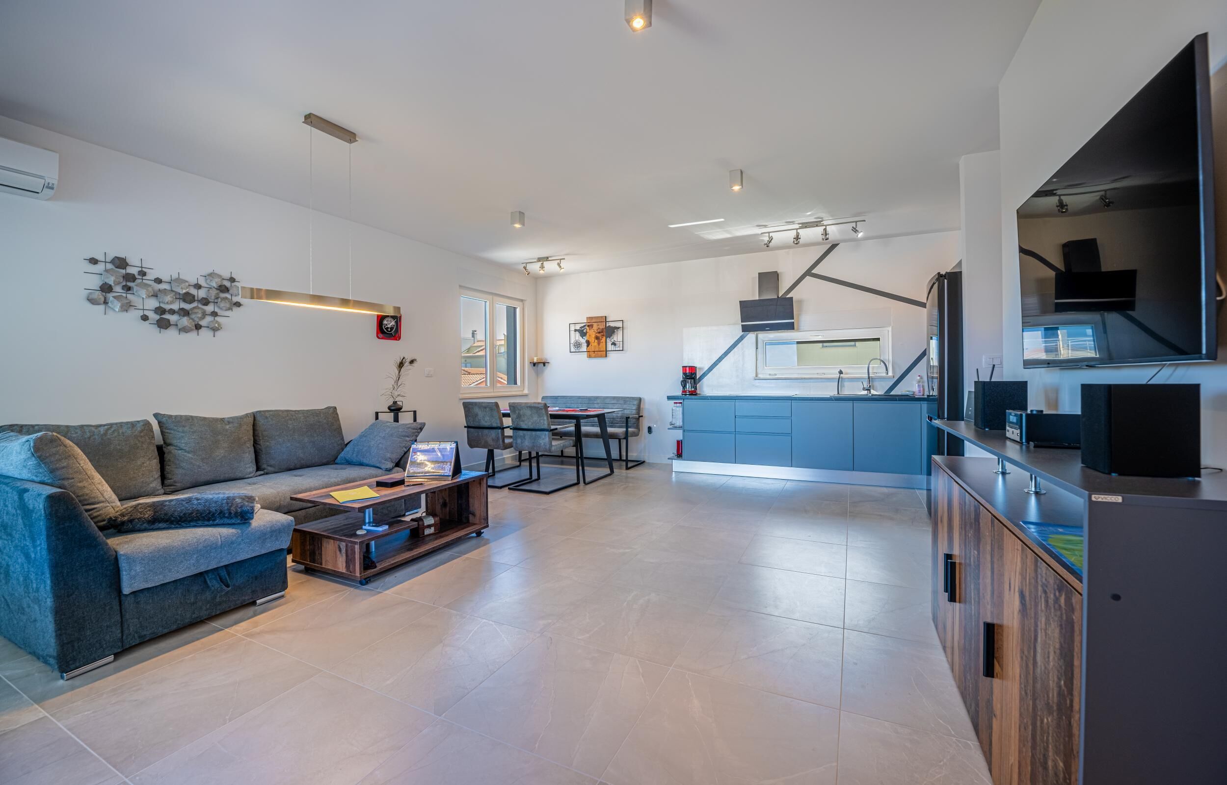 Un salon moderne comprenant un canapé, une table basse et un coin repas avec des chaises.