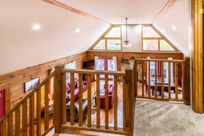 Un dormitorio tipo loft con una escalera de madera, un sofá rojo y una zona de comedor con mesa y sillas.