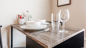 A neatly set dining table with white plates, bowls, and cutlery, a vase with a bird, and two wine glasses. - Fast WiFi, King Bed, Gym w/ Free Parking (Huntsville)