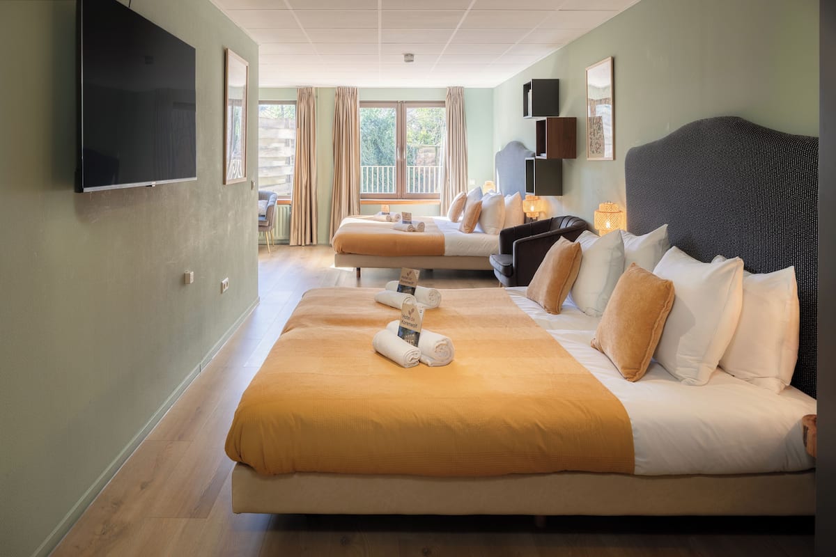 Une chambre d’hôtel avec un grand lit, une télévision, un balcon avec vue et un bureau équipé d’une lampe.