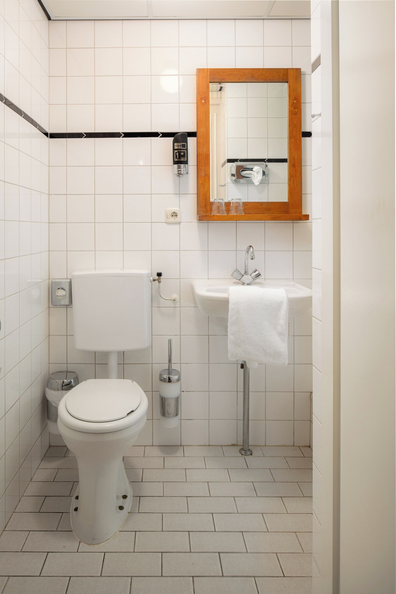 A small, clean bathroom with a toilet, sink, and mirror.