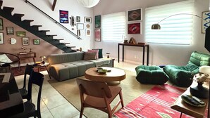 A modern living room with a staircase, a green sofa, a round coffee table, and a red rug. - Casa Felicidade, sua Estadia Perfeita em Belém! (Belém)