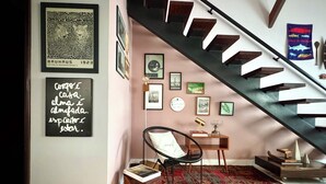 A staircase with a modern design, a black chair, a small table with a lamp, and a red patterned rug. - Casa Felicidade, sua Estadia Perfeita em Belém! (Belém)