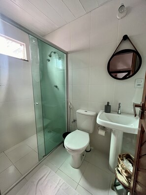 Une salle de bain avec une douche à parois de verre, des toilettes, un lavabo et un miroir.