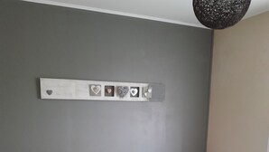 A bedroom with a bed, two nightstands, a wall-mounted light fixture, and a decorative piece above the bed. - Maison Chaleureuse Entièrement Clôturée Animaux Acceptés (Le Poinçonnet)