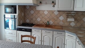 A kitchen with white cabinets, a gas stove, a dishwasher, and a tiled backsplash. - Maison Chaleureuse Entièrement Clôturée Animaux Acceptés (Le Poinçonnet)