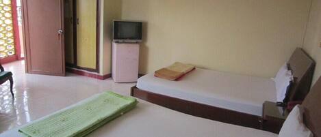 A hotel room with a bed, a small bedside table, a television, and a wardrobe.