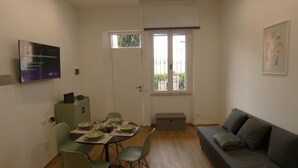 A dining area with a table set for four, a sofa, a television, and a window with a view of greenery. - Scappo in Umbria, Casaleo (Perugia)