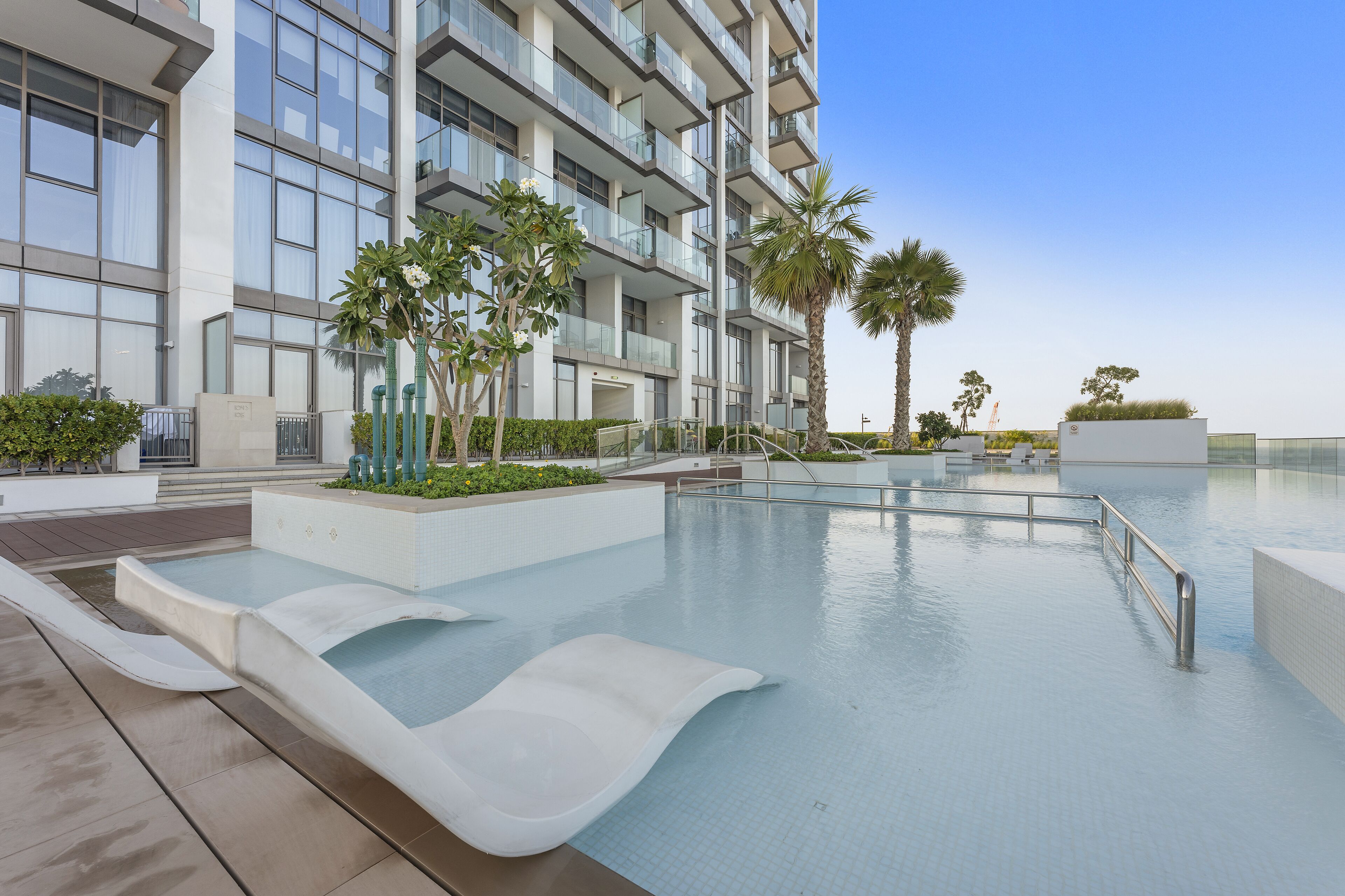 A modern building with a pool area, including a water slide and palm trees.