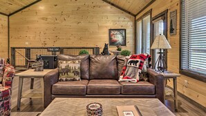 A cozy cabin interior with a leather sofa, a wooden ceiling, and a fireplace. - Wanderlust Pool Cabin: Private Pool, Hot Tub (Sevierville)