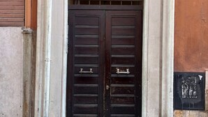 Una puerta doble de madera oscura con manijas de metal, ubicada en un edificio con fachada de piedra.