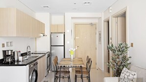 A modern kitchen with a dining area, built-in appliances, and a potted plant.