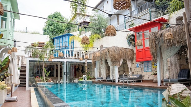 A pool area with a glass enclosure, lounge chairs, and a staircase leading to an upper level. - TNR Otel & Spa (Kusadasi)