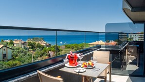 A balcony with a table set for two, overlooking a coastal view. - TNR Otel & Spa (Kusadasi)