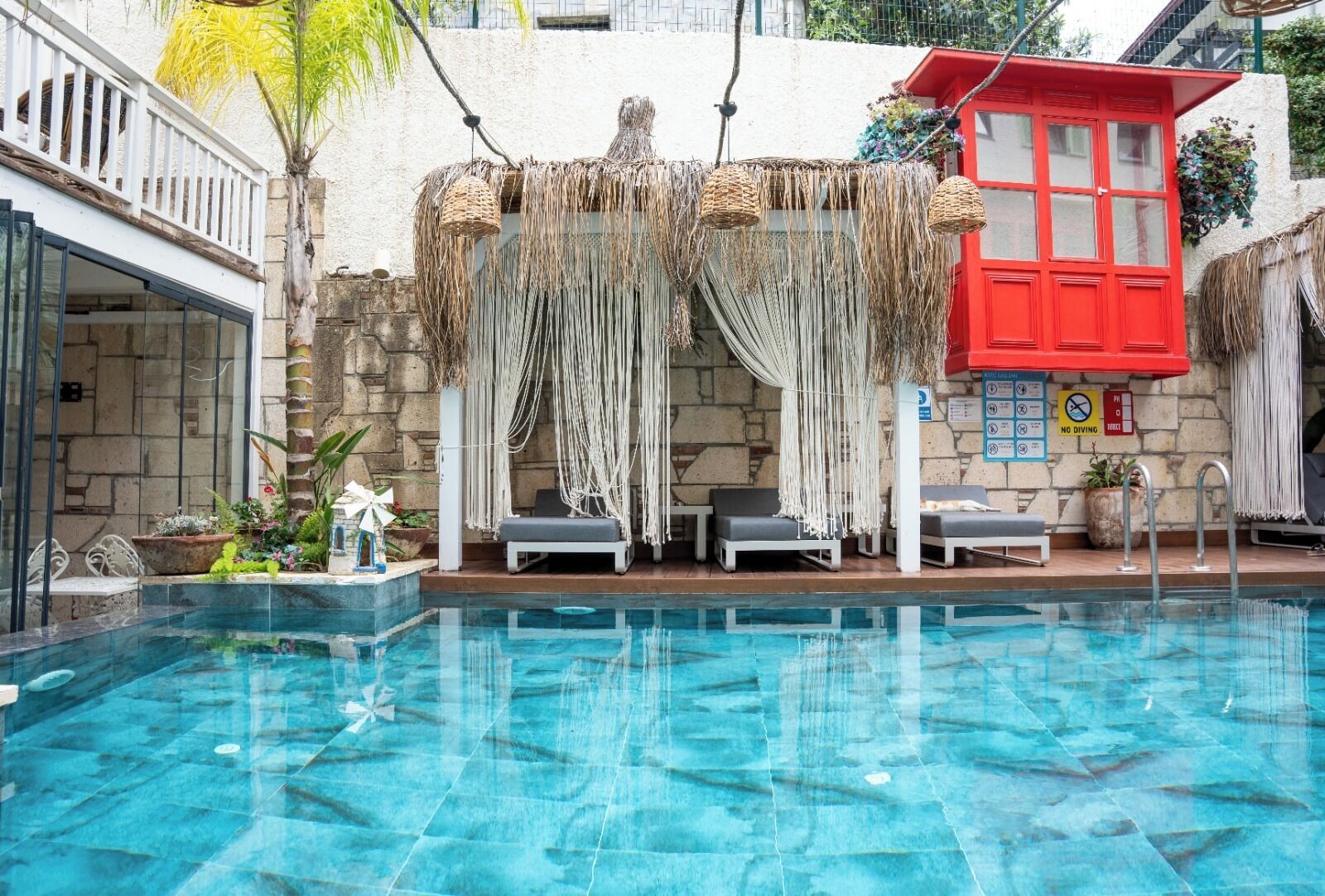 A swimming pool with lounge chairs and a red building in the background.