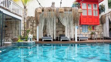 A swimming pool with lounge chairs and a red building in the background.