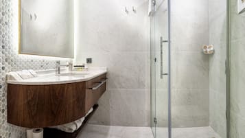 Un bagno moderno con una vasca lavabo in marmo, uno spazio doccia in vetro e un grande specchio.