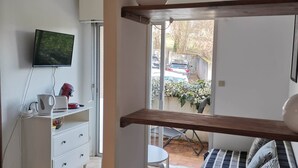 Un dormitorio con cama, televisión, escritorio y ventana.