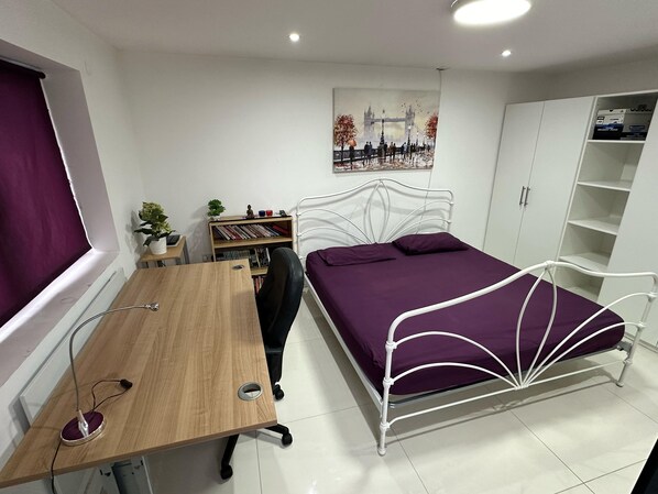 Un dormitorio con cama, escritorio, estantería y armario.