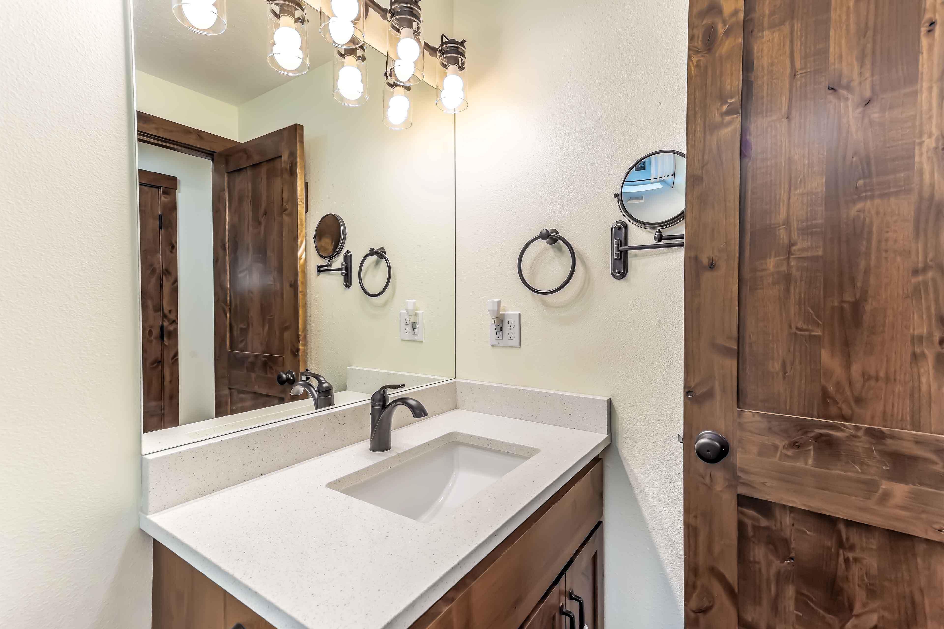 Une salle de bain avec un grand miroir, un lavabo et une porte en bois.