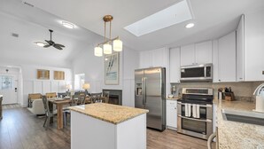 A modern kitchen with white cabinetry, stainless steel appliances, and a central island. - Pool, Pickleball & Putting Green Retreat (Jacksonville Beach)